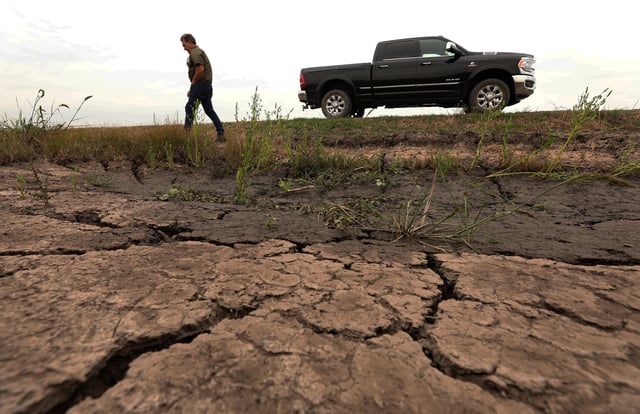 A farmer near Kaplan, Louisiana, walks by dry cracked earth on his farm impacted by exceptional drought in 2023.