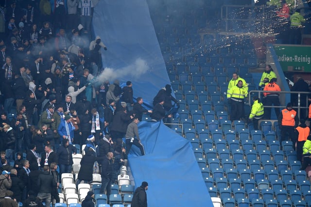 Ein Fußballfan schießt mit Pyrotechnik auf Menschen in einem anderen Block
