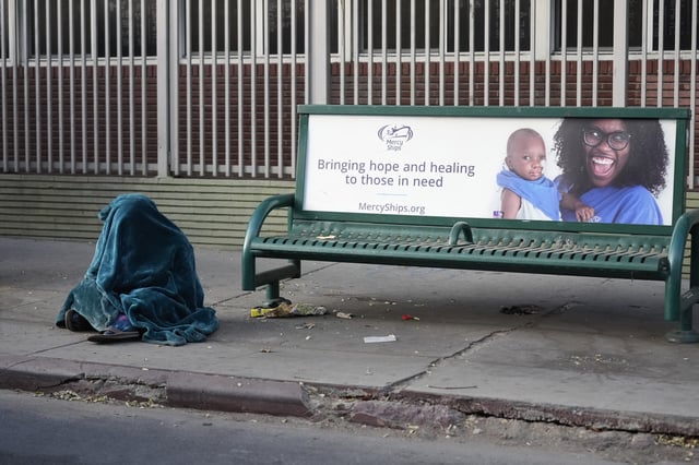 A homeless person sits on a sidewalk in Los Angeles, Tuesday, Jan. 21, 2025.