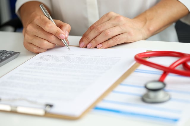 Stock image/file photo: Doctor filling out medical form.