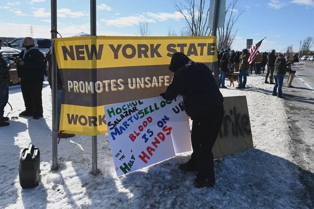 Striking corrections officers demonstrate in Coxsackie on Feb. 19. A protester's sign names the governor, chair of the state Senate corrections committee, and corrections commissioner.