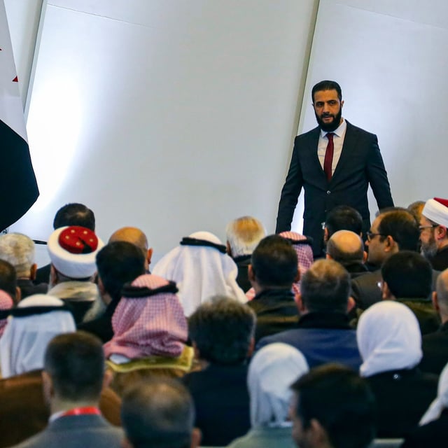 Syria's interim president Ahmad al-Sharaa, right, leaves the podium after speaking during Syria's national dialogue conference at the People’s Palace in Damascus, Syria, Tuesday Feb. 25, 2025. (AP Photo/Omar Albam)
