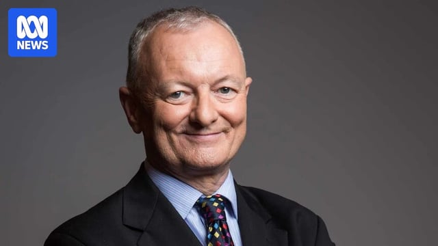 ABC election expert Antony Green smiles at the camera with his hands clasped behind his back.