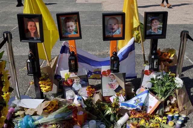 People walk around a makeshift memorial in front of portraits of late Israeli hostages Shiri (L), Ariel (CL), and Kfir (CR) Bibas, as well as Oded Lifshitz (R) at Hostages Square in Tel Aviv on February 25, 2025, a day ahead of the Bibas family funeral.