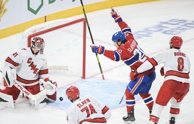 Montreal Canadiens' Juraj Slafkovsky (20) reacts to a goal by teammate Lane Hutson (not shown) on Carolina Hurricanes goaltender Frederik Andersen (31) as Hurricanes' Jaccob Slavin (74) and Brent Burns (8) defend during third period NHL hockey action in Montreal, Tuesday, February 25, 2025. 