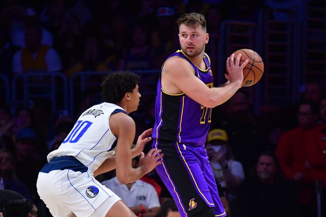 Feb 25, 2025; Los Angeles, California, USA; Los Angeles Lakers guard Luka Doncic (77) looks to move the ball on Dallas Mavericks guard Max Christie (00) during the first quarter at Crypto.com Arena. Mandatory Credit: Gary A. Vasquez-Imagn Images