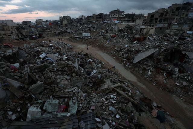 Palestinians walk among the rubble of destroyed buildings in Khan Younis, in the southern Gaza Strip, on February 24, 2025.