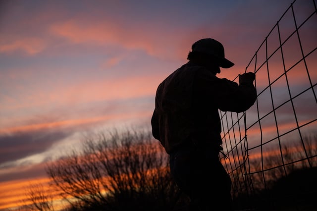 A farmer fixes a broken barn fence on February 23, 2023 in Quemado, Texas.