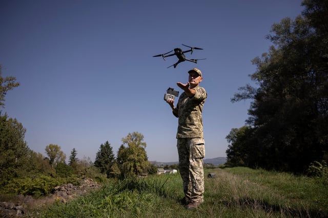 A Ukrainian border guard launches a drone he uses to survey the border to Romania in Tyachiv, September 26, 2023.  REUTERS/Thomas Peter/File Photo