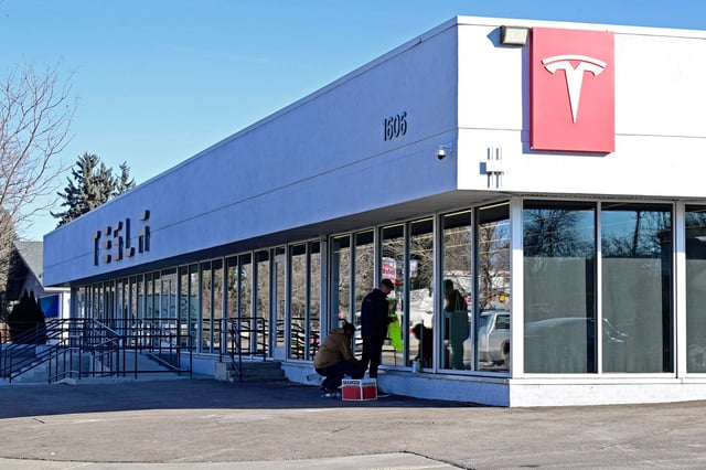 People clean graffiti off of the windows on Friday, Feb. 7, 2024, at the Tesla dealership in Loveland.    Officials said the vandalism included someone trying to set the dealership on fire. (Jenny Sparks/Loveland Reporter-Herald)