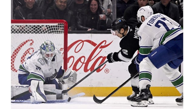 Vancouver Canucks goaltender Kevin Lankinen, left, stops a shot by Kings left wing Trevor Moore with defenseman Derek Forbort, right, defending during the third period on Wednesday night at Crypto.com Arena. The Kings rallied with two third-period goals to force overtime, but lost, 3-2. (AP Photo/Alex Gallardo)