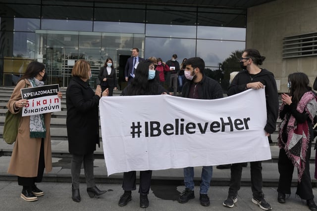 FILE - Lawyer Michael Polak, background, is seen as protesters hold banners in support of a British woman, outside of Cyprus' Supreme Court in the capital Nicosia on Monday, Jan. 31, 2022. (AP Photo/Petros Karadjias, File)