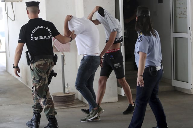 FILE - Suspects cover their faces with their shirts as they arrive at the Famagusta courthouse in Paralamni, Cyprus, Friday, July 26, 2019. (AP Photo/Petros Karadjias, File)