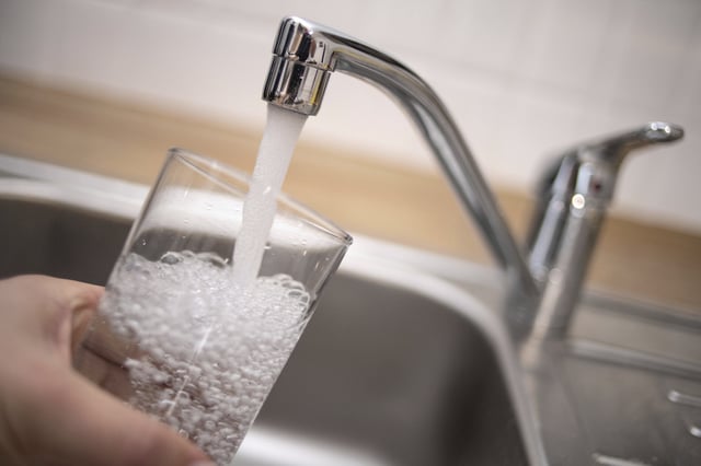 File photo of a man holding a glass of water under a tap, taken in North Rhine-Westphalia, Duesseldorf, in 2019.