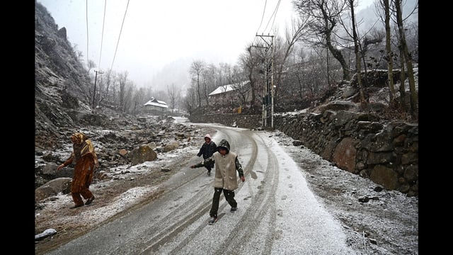 People walk during snowfall on the outskirts of Srinagar on Thursday. (Waseem Andrabi /HT)