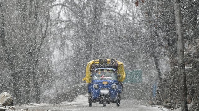 An auto rickshaw moves during snowfall on the outskirts of Srinagar.