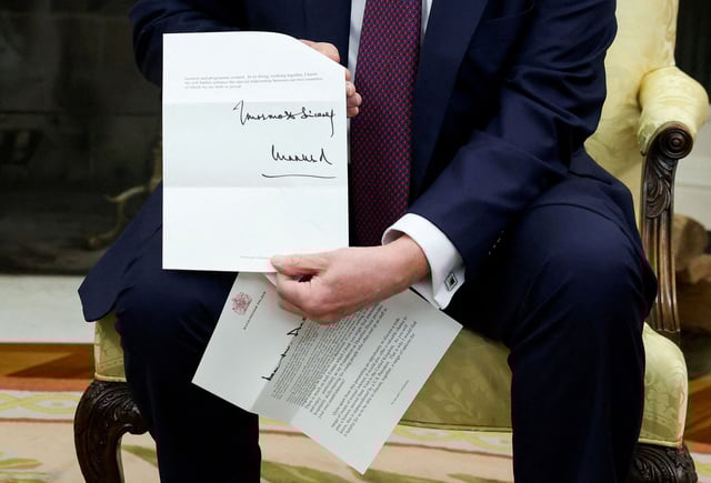 US President Donald Trump holds a letter from Britain's King Charles as he meets with British Prime Minister Keir Starmer in the Oval Office on February 27, 2025.