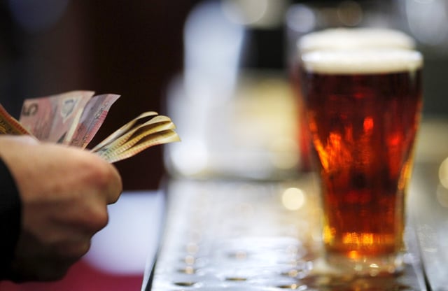 A customer pays for a Fosters beer at the Occidental Hotel in central Sydney in this June 21, 2011 file photo. REUTERS/Tim Wimborne/File Photo