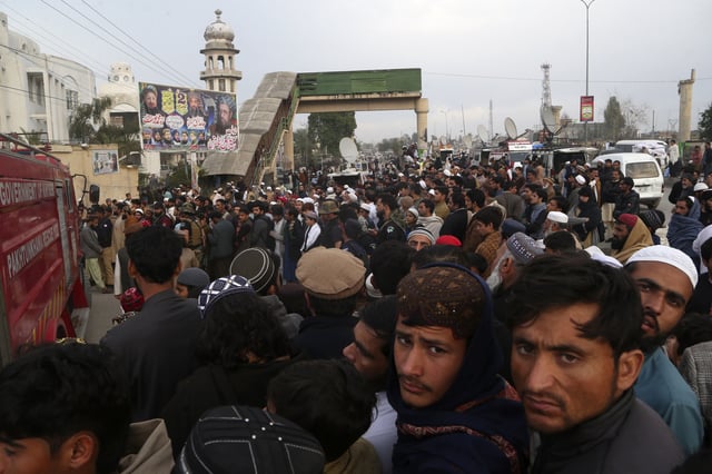 People gather outside a pro-Taliban seminary 'Darul Uloom Haqqania' following a suicide bombing in a mosque, in Akora Khattak, a district in the Pakistan's northwestern Khyber Pakhtunkhwa province, Friday, Feb. 28, 2025. (AP Photo/Muhammad Sajjad)