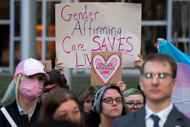 People hold pro-trans signs after a hearing in the multi-state lawsuit over President Trump's order ending all federal funding or support for healthcare that aids gender transitions for people younger than 19, outside a courthouse in Seattle, Washington, U.S., February 28, 2025.