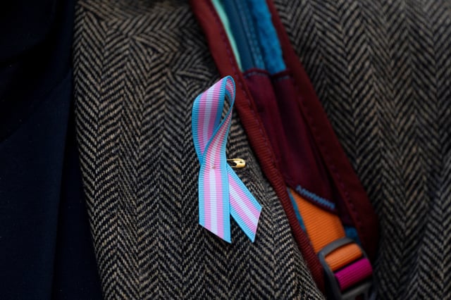 A supporter wears a pro-trans ribbon after a hearing in the multi-state lawsuit over President Trump's order ending all federal funding or support for healthcare that aids gender transitions for people younger than 19, outside a courthouse in Seattle, Washington, U.S., February 28, 2025.