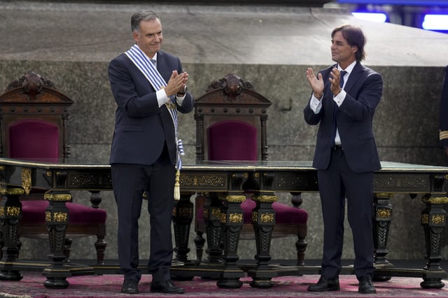 Uruguay's incoming President Yamandu Orsi, left, shows his appreciation after receiving the presidential sash from outgoing President Luis Lacalle Pou, on Inauguration Day in Montevideo, Uruguay, Saturday, March 1, 2025. (AP Photo/Matilde Campodonico)