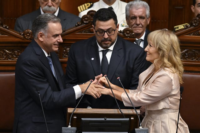 Uruguay's President-elect Yamandu Orsi holds hands with Vice President-elect Carolina Cosse, accompanied by Sen. Alejandro Sanchez, during their swearing-in ceremony in Congress on Inauguration Day, in Montevideo, Uruguay, Saturday, March 1, 2025. (AP Photo/Santiago Mazzarovich)