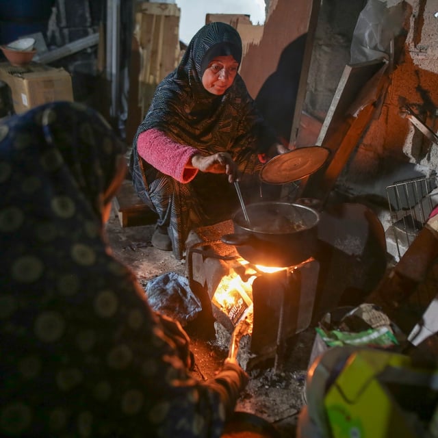 Fatima Al-Absi prepares food for her family's iftar, the fast-breaking meal, on the first day of Ramadan in their damaged apartment in Jabaliya, northern Gaza Strip, on Saturday, March 1, 2025. (AP Photo/Jehad Alshrafi)
