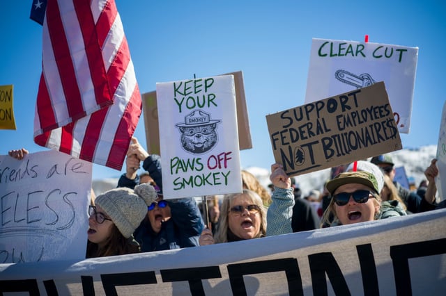 Protesters hold signs at Roosevelt Arch, the northern entrance to Yellowstone Park in Gardiner, Mont., on March 1, 2025.