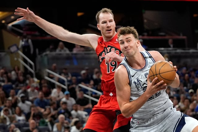 Orlando Magic forward Franz Wagner, right, makes a move to the basket in front of Toronto Raptors center Jakob Poeltl (19) during the first half of an NBA basketball game Sunday, March 2, 2025, in Orlando, Fla. (AP Photo/John Raoux)
