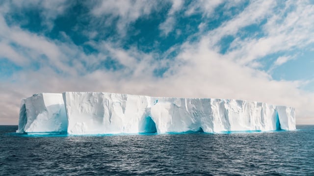 Gigantic Tabular Iceberg with many natural Ice Arches floating on the Antarctic Ocean.