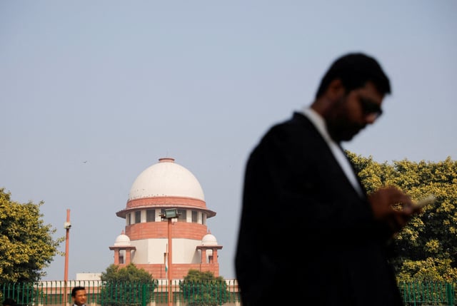 A lawyer looks into his mobile phone in front India's Supreme Court in New Delhi, December 11, 2023. REUTERS/Adnan Abidi/File Photo