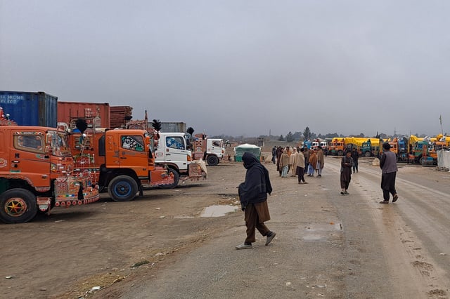 People move past parked trucks loaded with supplies at the Torkham border crossing following the closure of the border crossing between Pakistan and Afghanistan, March 3, 2025. REUTERS/Shahid Shinwari