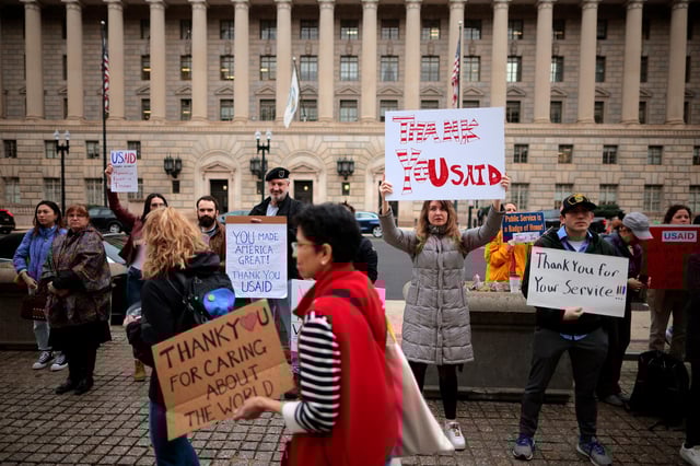 Supporters hold signs as former US Agency for International Development employees on February 27, in Washington, DC.