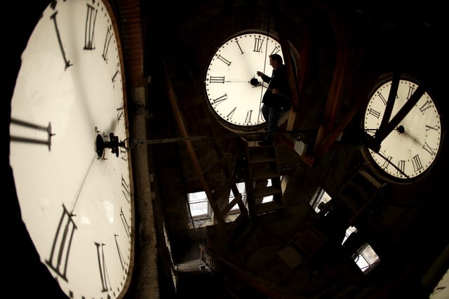 FILE - Custodian Ray Keen inspects a clock face before changing the time on the 100-year-old clock atop the Clay County Courthouse, March 8, 2014, in Clay Center, Kansas. (AP Photo/Charlie Riedel, File)