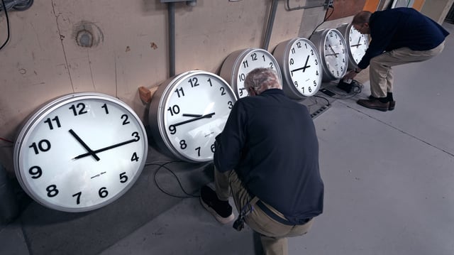 Clockmakers Rich Finn and Tom Erb adjust the time zone controllers on a series of clocks in Medfield, Massachusetts, on October 30, 2024.