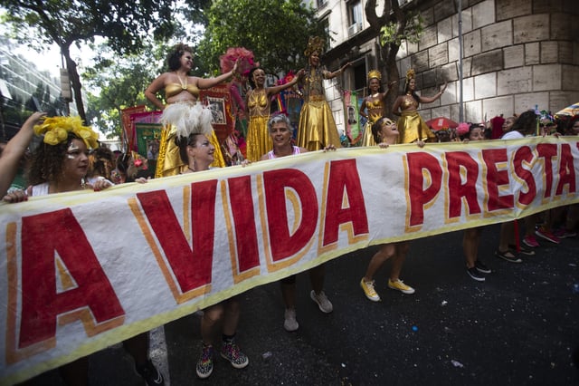 Revelers hold a banner that reads in Portuguese; "Life is worth it," in tribute to Brazilian actress Fernanda Torres, who's competing for the best actress Oscar for her role in "I'm Still Here", at the "Cordao do Boitata" street pre-carnival party in Rio de Janeiro, Sunday, Feb. 23, 2025. (AP Photo/Bruna Prado)