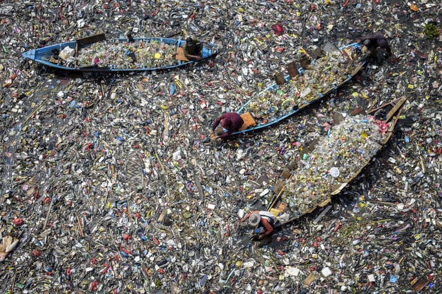 People on boats collect recyclable plastics from the heavily polluted Citarum River at Batujajar in Bandung, West Java, on June 12, 2024.