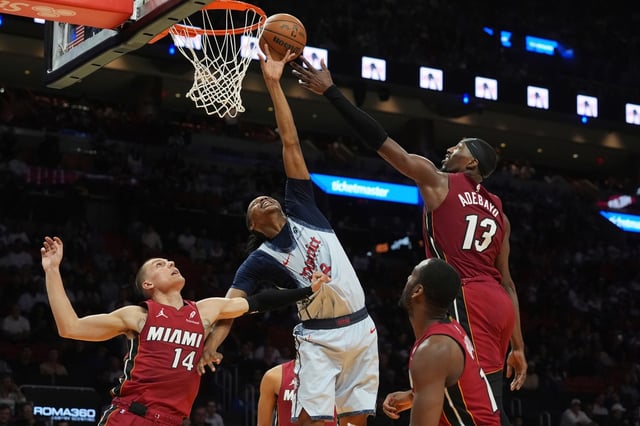 Washington Wizards guard Bub Carrington (8) and Miami Heat center Bam Adebayo (13) battle for a rebound during the first half of an NBA basketball game, Monday, March 3, 2025, in Miami. (AP Photo/Marta Lavandier)