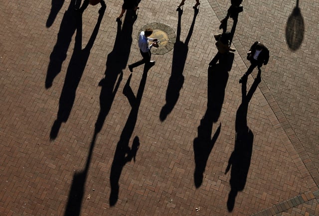 Commuters cast their shadows as they arrive in the Central Business District during the morning rush hour in Sydney July 1, 2013.  REUTERS/Daniel Munoz/File Photo