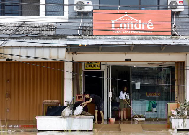 People clean their shop from mud after floods hit the residential area following heavy rains in Bekasi, on the outskirts of Jakarta, Indonesia, March 4, 2025. REUTERS/Ajeng Dinar Ulfiana