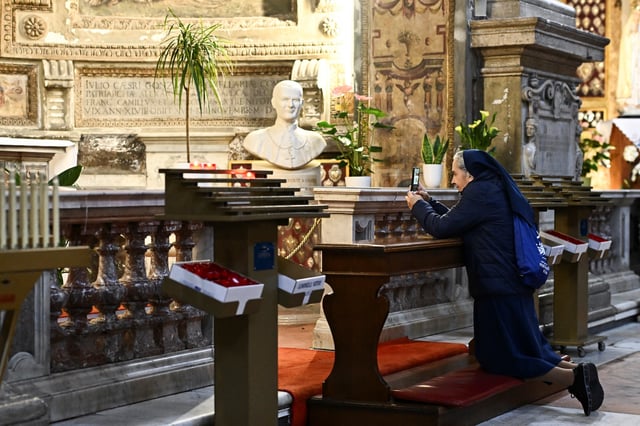 A nun takes a picture in the Santo Spirito in Sassia Church, as Pope Francis continues his hospitalization, in Rome, Italy, March 4, 2025. REUTERS/Dylan Martinez