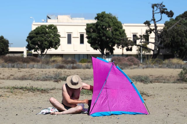 A man builds a shade structure on Alameda Beach during a heat wave in the Bay Area on Oct. 2. As climate change makes extreme heat events more common, a new study says older adults who live in very hot regions may age faster biologically than those in cooler climates.