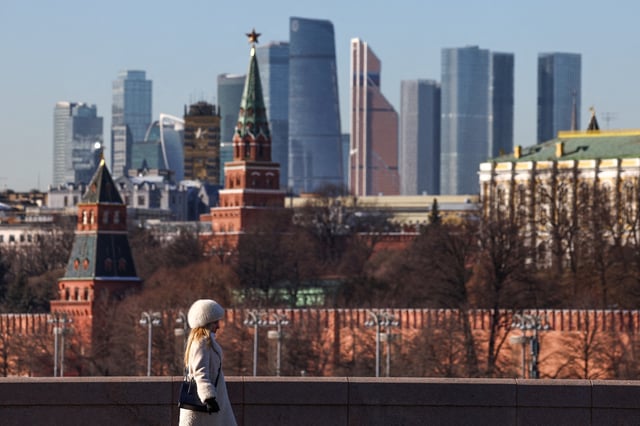 A woman walks along a bridge, with the Moscow City business centre and the Kremlin wall seen in the background, on a sunny day in Moscow, Russia, February 24, 2025. REUTERS/Evgenia Novozhenina/File Photo