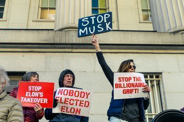 Protesters holding signs reading "Stop Elon's Takeover," "Nobody Elected Musk" and Stop the Billionaire Grift