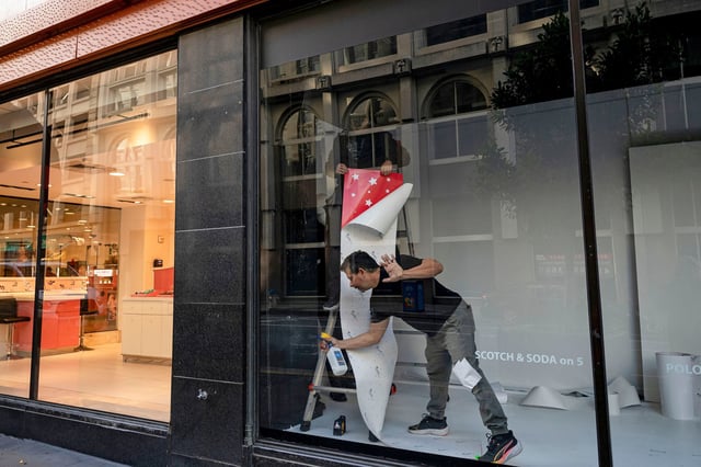 Workers install window decorations at a store in San Francisco in November 2024.