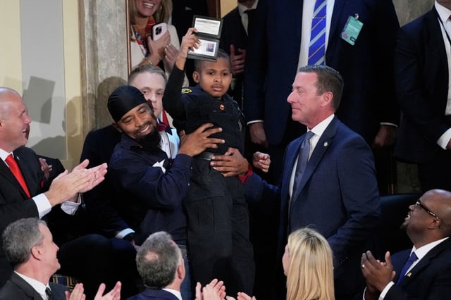 Devarjay &#34;DJ&#34; Daniel holds and honorary U.S. Secret Service special agent id, presented to him by director of the U.S. Secret Service Sean Curran, right, as President Donald Trump addresses a joint session of Congress at the Capitol in Washington, Tuesday, March 4, 2025.