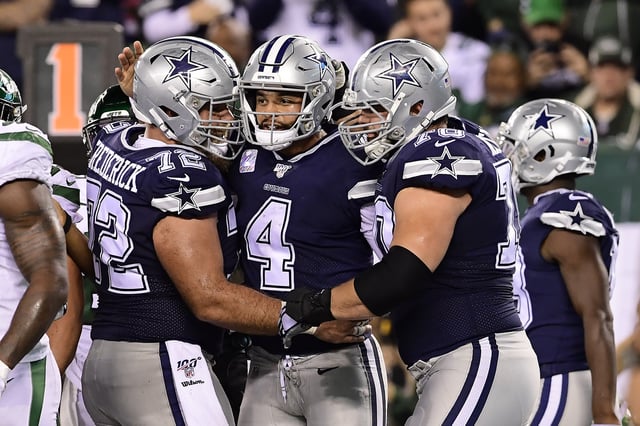 EAST RUTHERFORD, NEW JERSEY - OCTOBER 13: Dak Prescott #4 of the Dallas Cowboys is congratulated by his teammates Travis Frederick #72 and Zack Martin #70 after scoring a rushing touchdown against the New York Jets during the fourth quarter at MetLife Stadium on October 13, 2019 in East Rutherford, New Jersey.