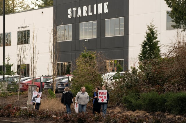 Demonstrators hold signs during a protest outside SpaceX and Starlink facilities in Redmond, Washington, U.S., February 26, 2025.  REUTERS/David Ryder/File Photo