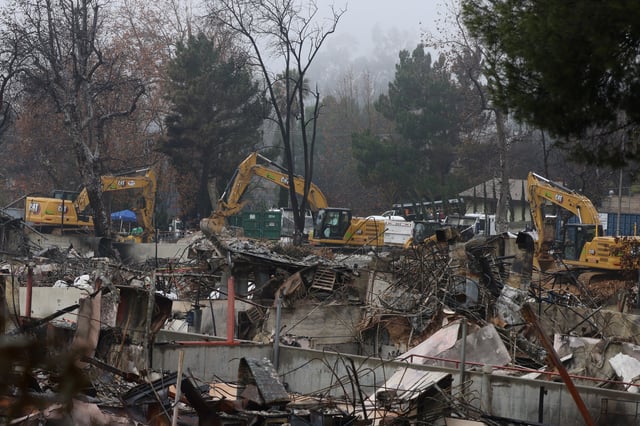 Workers in heavy machinery gather and haul dirt, concrete, and legacy building materials from a destroyed school, Loma Alta Elementary School, burned in the Eaton Fire in Altadena, California, U.S. February 5, 2025.  REUTERS/David Swanson/File Photo